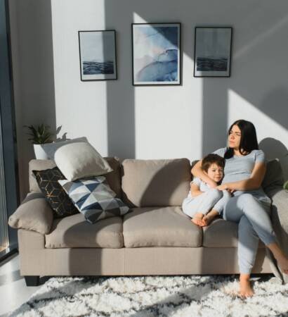 Young mother with her 4 years old little son dressed in pajamas are relaxing and playing in the bed at the weekend together, lazy morning, warm and cozy scene.